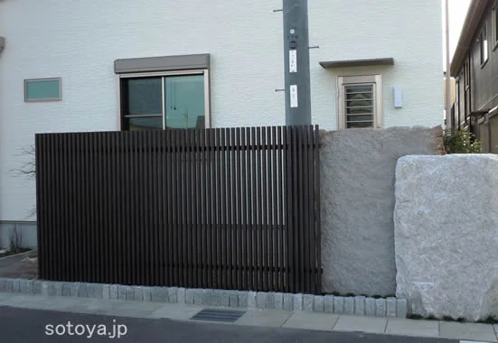 木目の縦格子と一枚ものの板石で目隠し